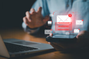 Porque é que as campanhas de phishing são bem sucedidas? O homem de negócios que usa o smartphone e o computador mostra um sinal de aviso depois de ter recebido um e-mail de phishing atacado por malware de um hacker que comete um crime cibernético ou uma falha de software que causa um erro.